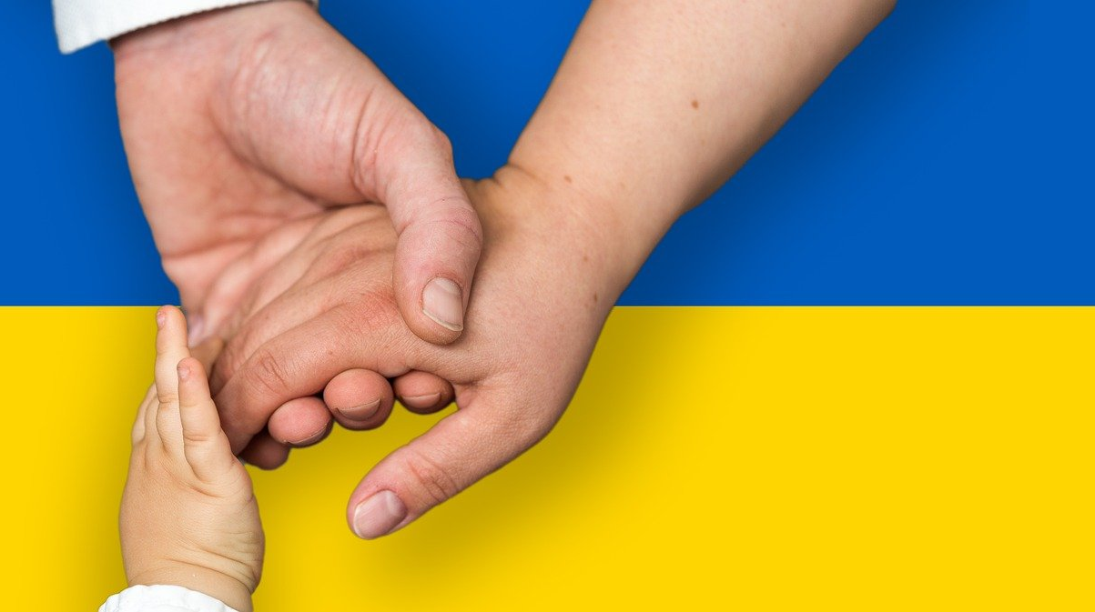 Bild: Ukrainische Flagge, mit sich greifenden Händen davor. Quelle: Pixabay
